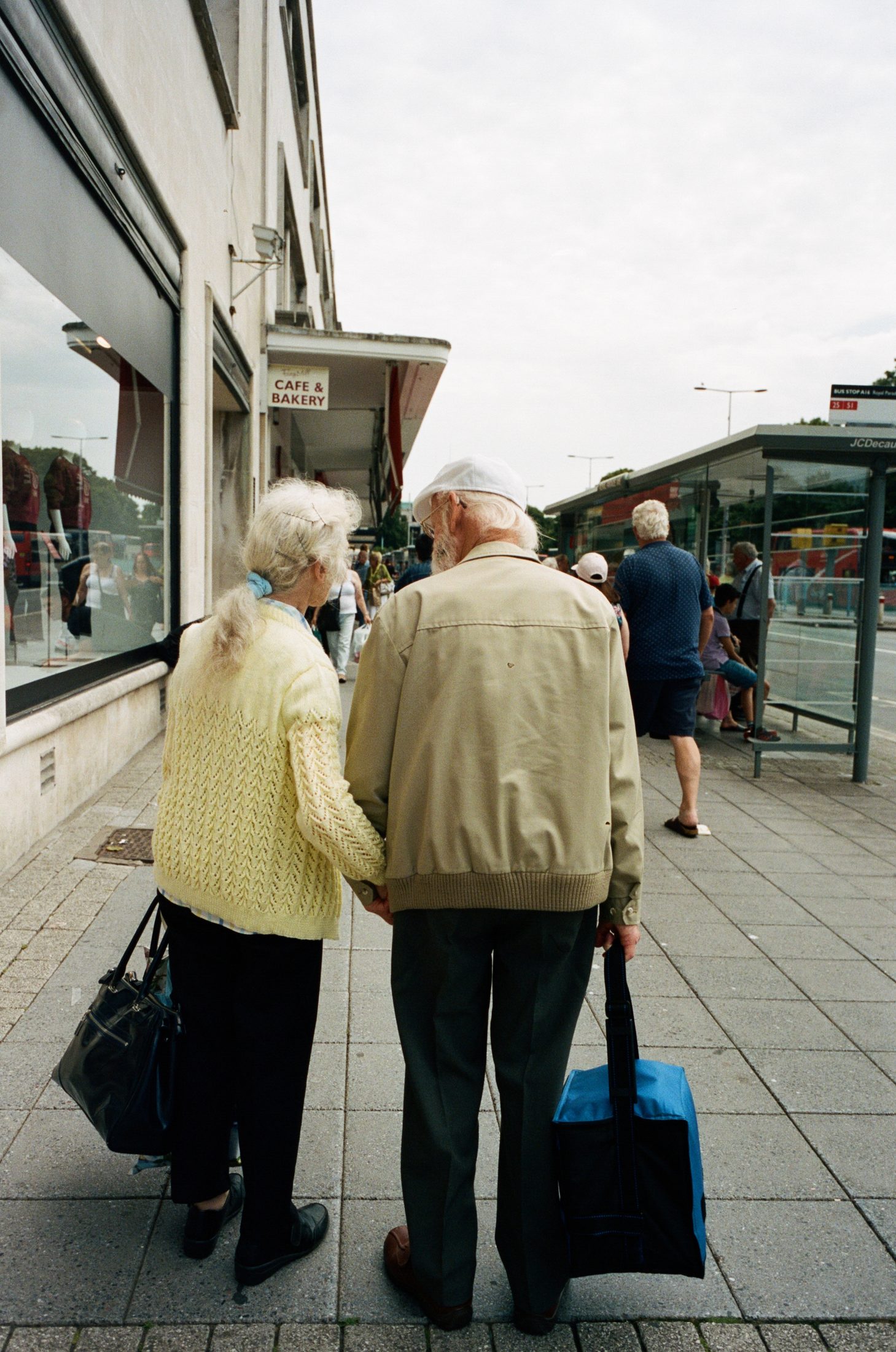Elderly couple walking with a blue suitcase, English seaside