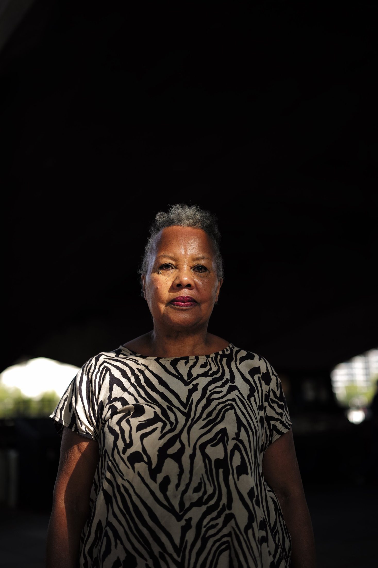 Older woman in a zebra-print top, emerging from darkness
