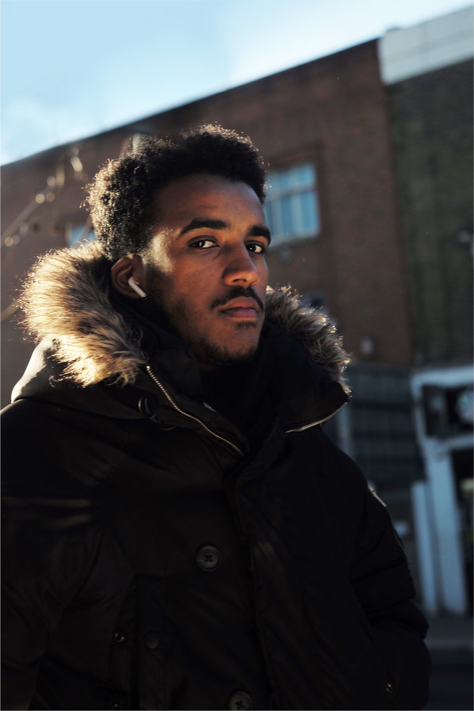 Young man in a fur-lined hood, winter sun on his face
