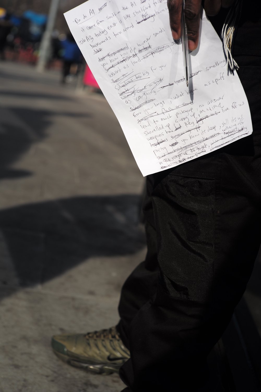 Handwritten notes held in sunlight above the pavement