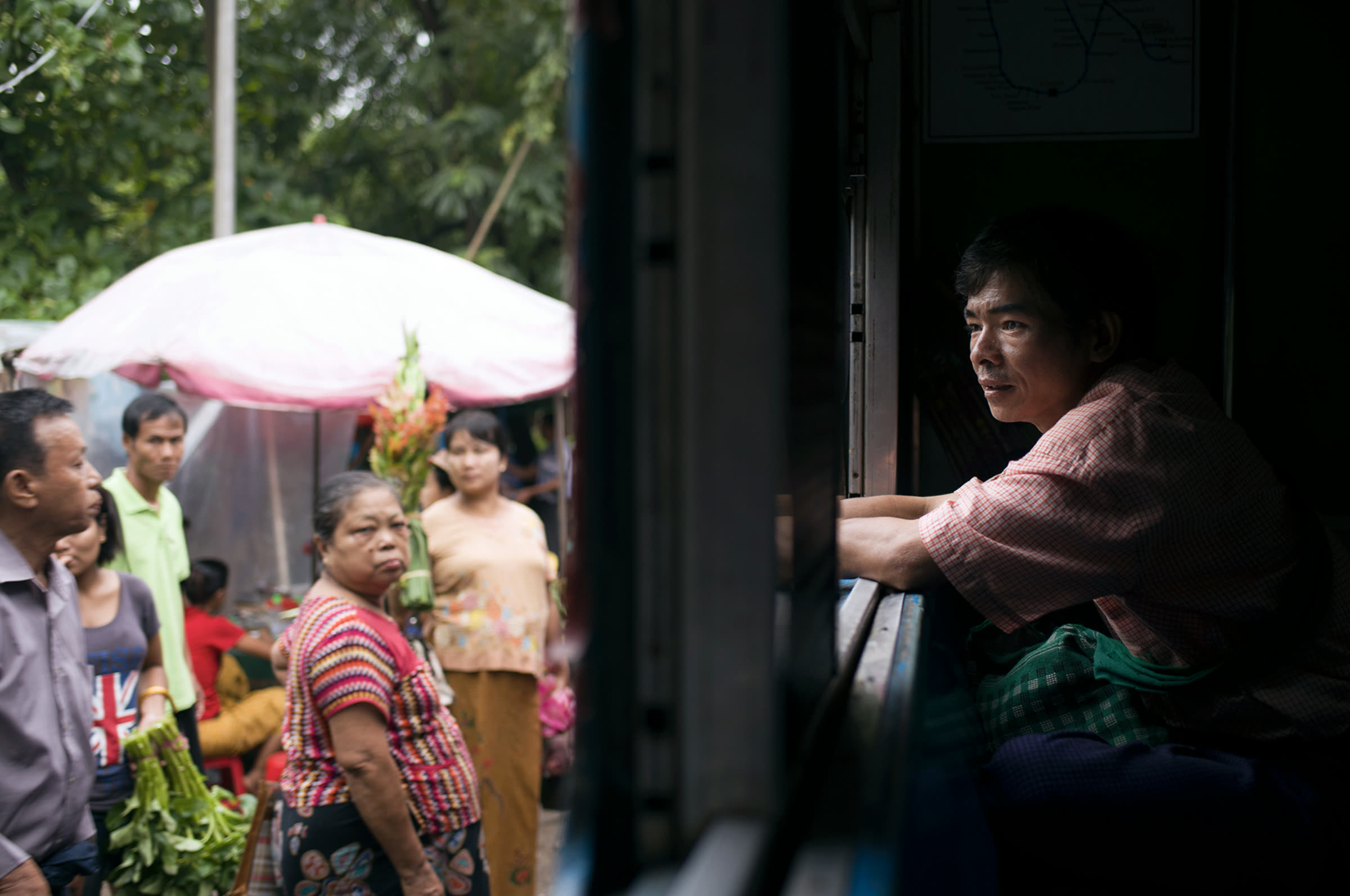 A passenger at the window of the Mandalay Express, the market beyond