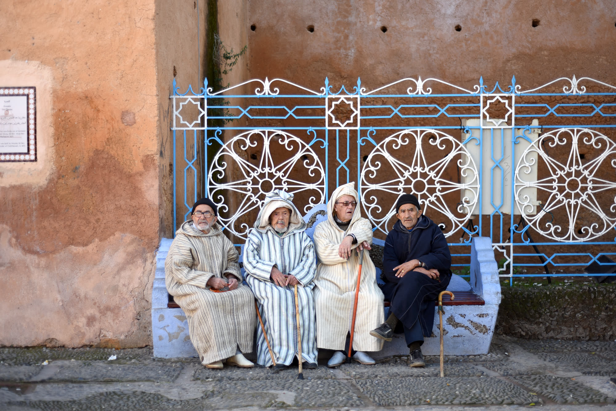 Four men in djellabas on a bench, Chefchaouen