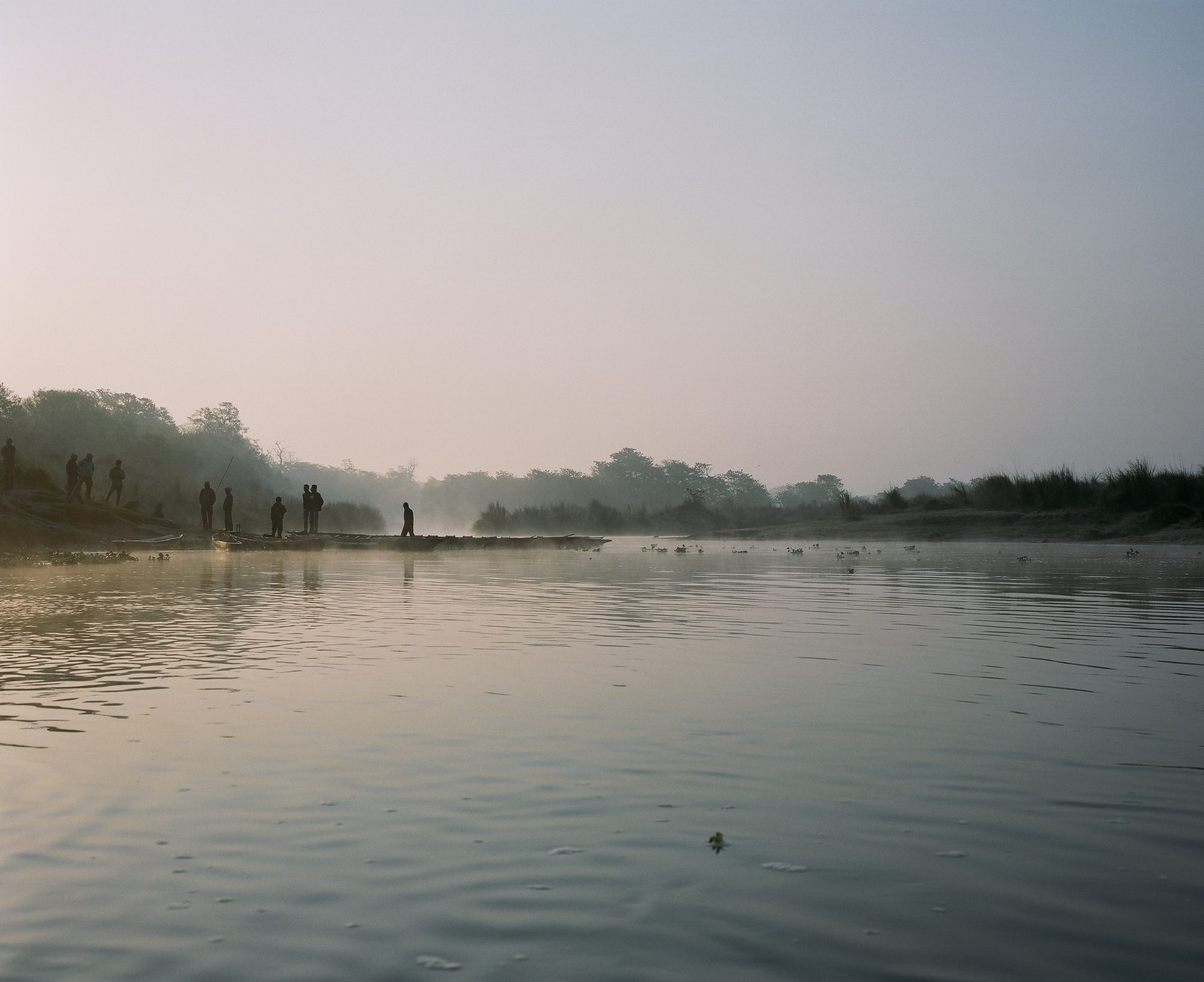 Figures by the river in morning mist