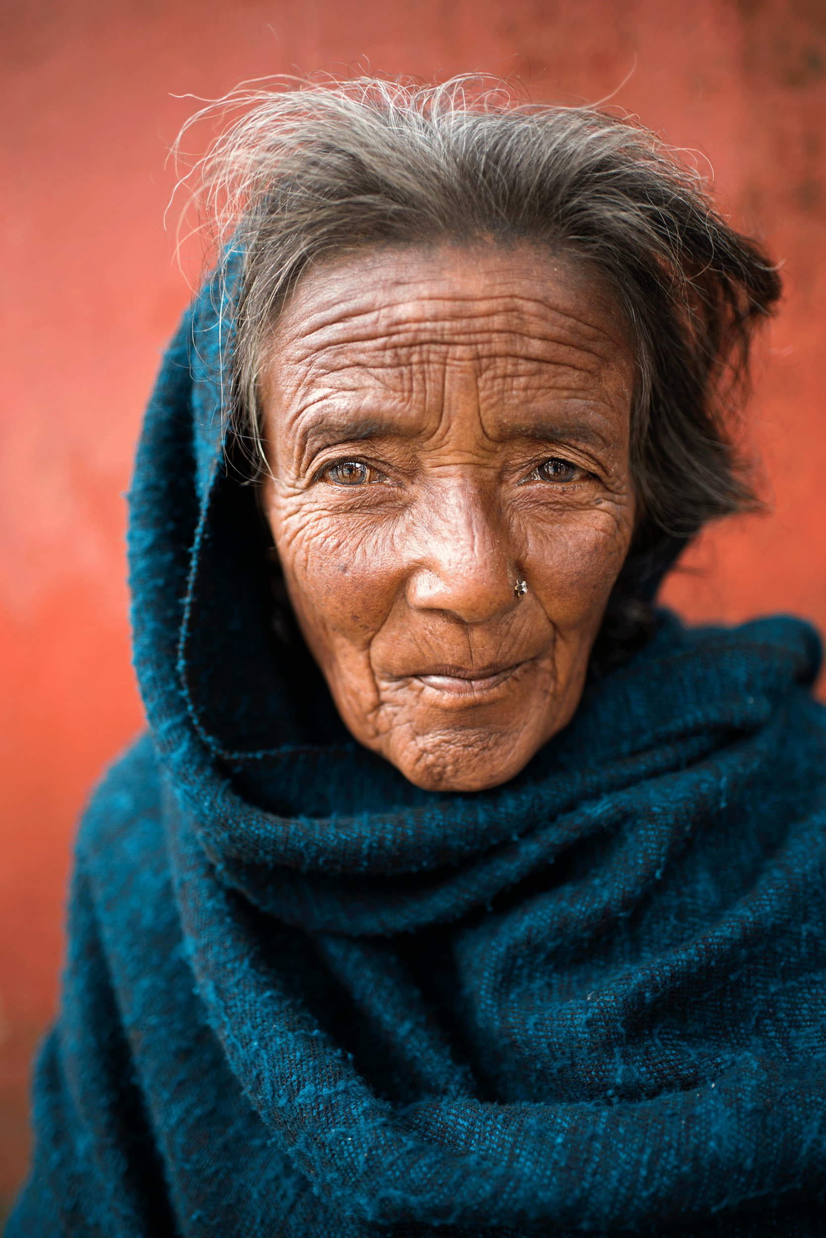 Portrait of a cigarette vendor against a red wall, Nepal